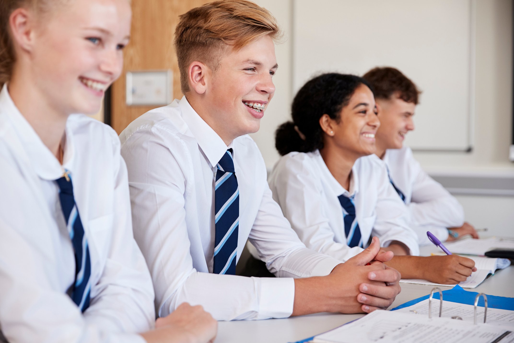 Line of High School Students Wearing Uniform Sitting at Desk in